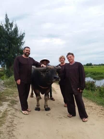 Guest walking a water buffalo through the fields